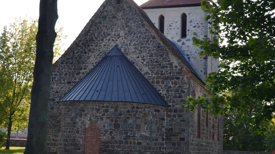 A stone church with a pointed roof and a bell tower.