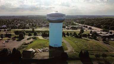 A large water tower labeled 'Farmington' surrounded by a green landscape with trees and a road.