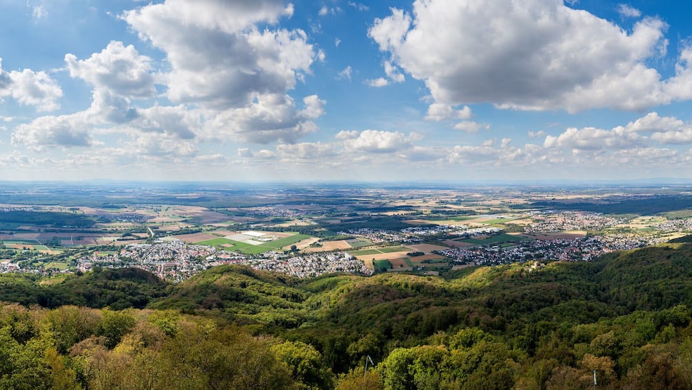 Une vue panoramique d’une ville nichée dans une vallée, entourée de collines, sous un ciel dégagé.