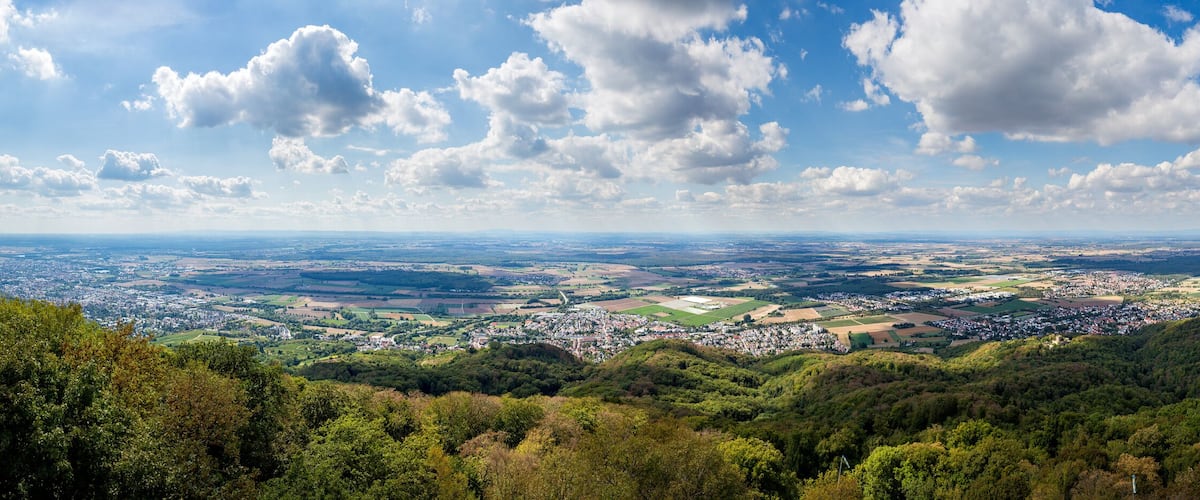 A panoramic view of a town nestled in a valley with surrounding hills and a clear sky.