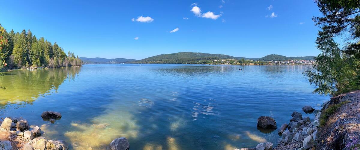A calm lake surrounded by dense forests and hills.