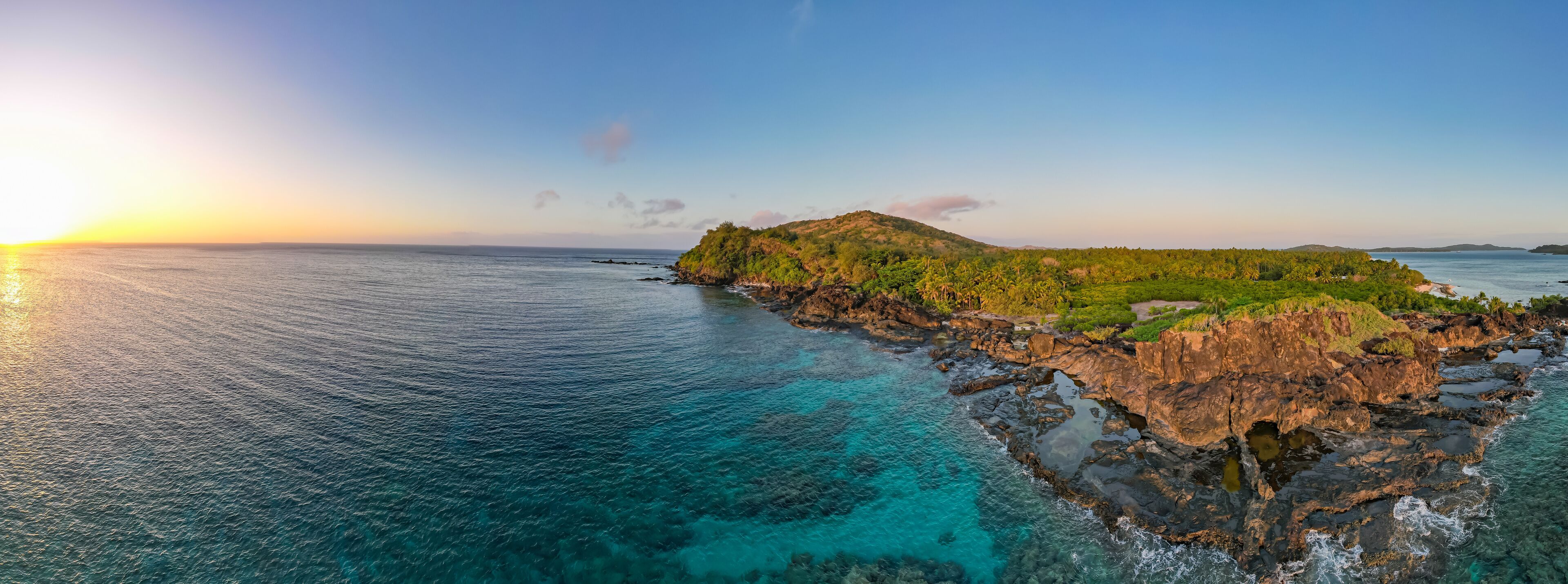 A coastal landscape with clear turquoise waters, rocky cliffs, and lush greenery.