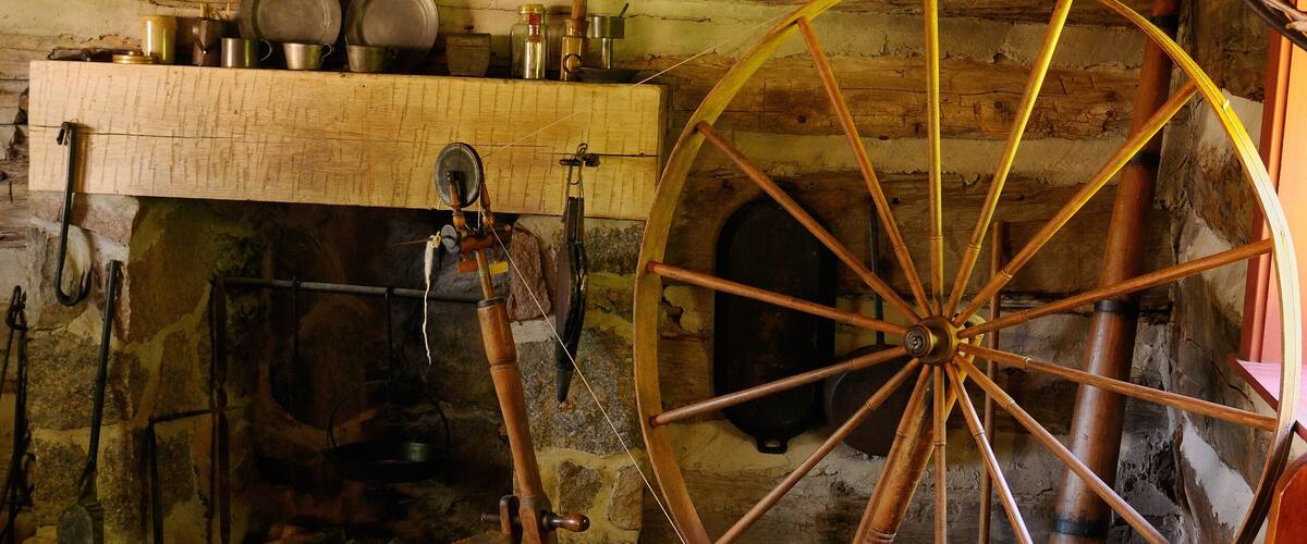 Primitive one room log cabin with beds and fireplace at Lang Pioneer Village