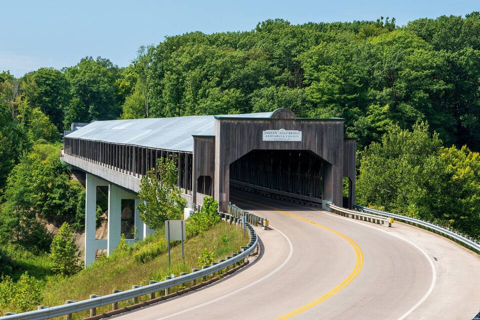 Un pont cobert amb un senyal que diu "Smolen - Gulf Bridge Ashtabula County Highway 27" en una zona boscosa.