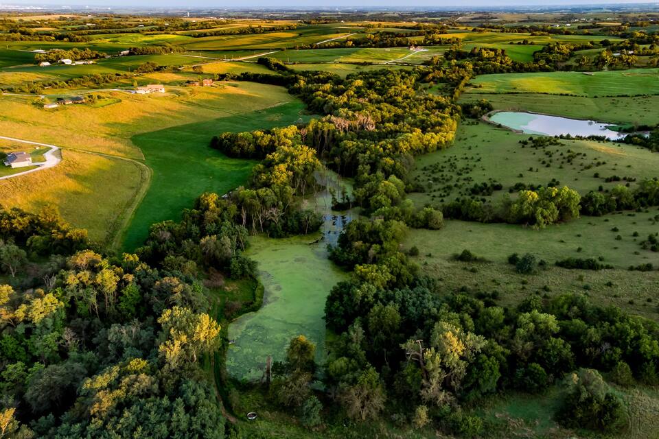 A golf course with water hazards, dense forests, and scattered buildings.