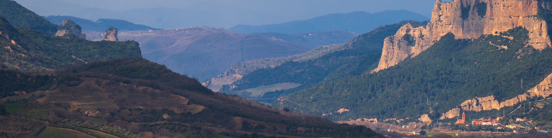 Un pueblo enclavado en un valle, con un castillo imponente en una colina.