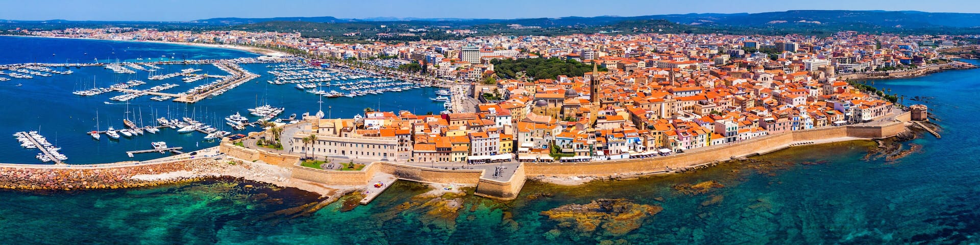 Aerial view over Alghero old town, cityscape Alghero view on a beautiful day with harbor and open sea in view. Alghero, Italy. Panoramic aerial view of Alghero, Sardinia, Italy.