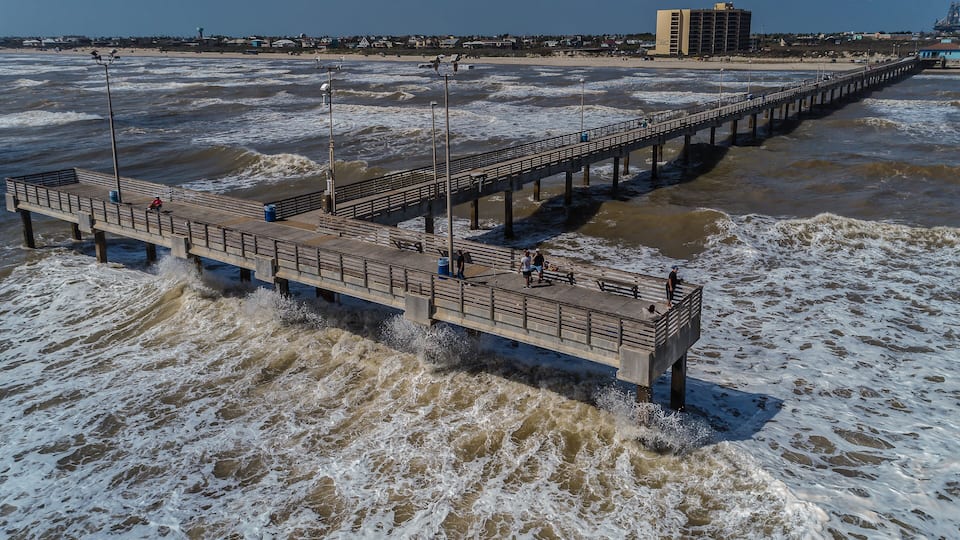 A pier extending into the ocean with waves crashing against it.