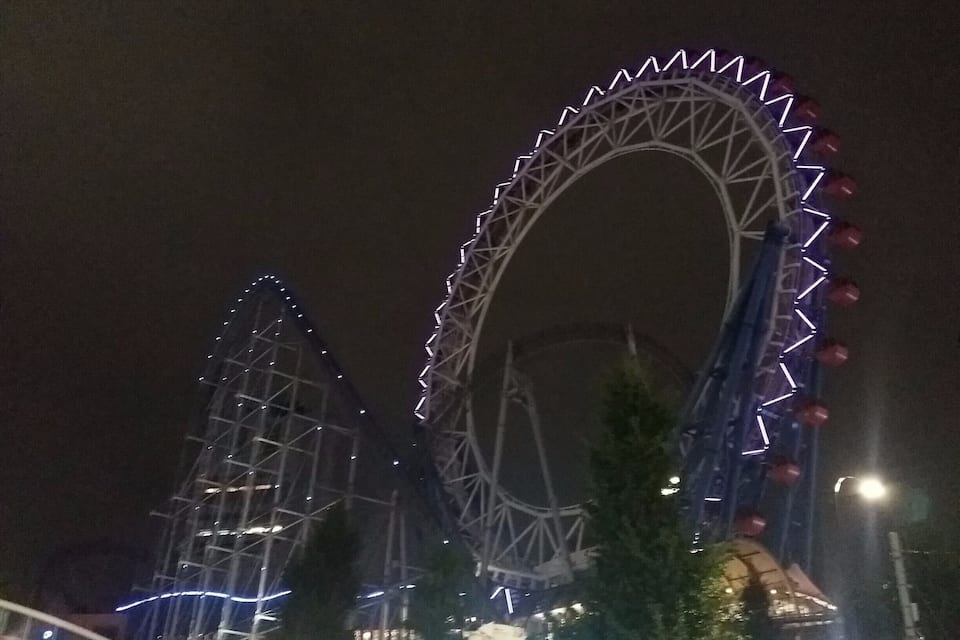 A large Ferris wheel with a partially constructed roller coaster nearby.
