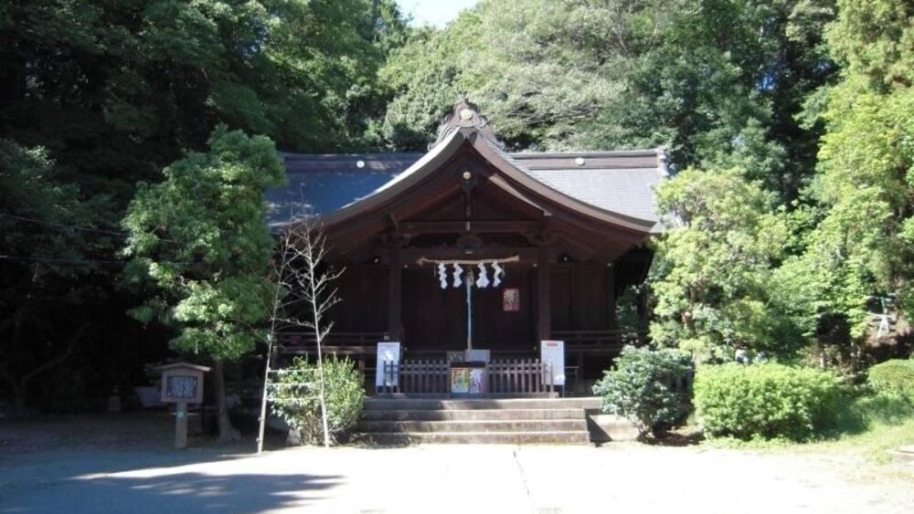 A traditional Japanese building with a curved roof, surrounded by lush greenery.