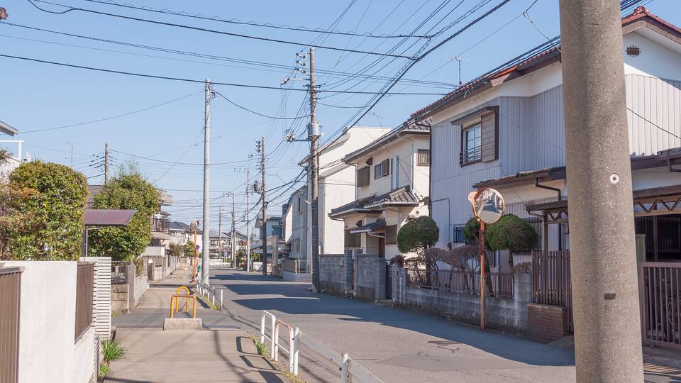 A residential street with houses, utility poles, and a clear sky.