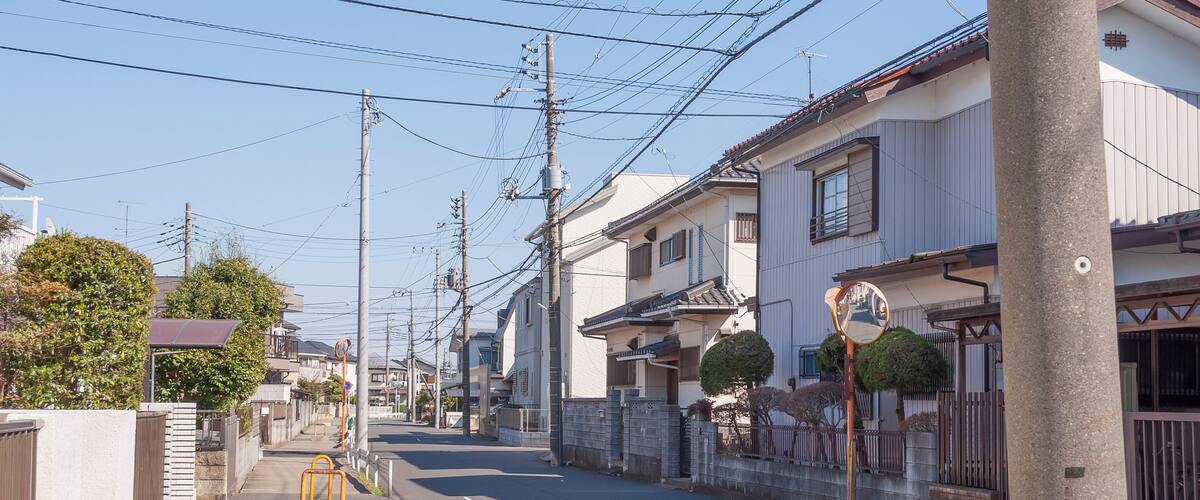 A residential street with houses, utility poles, and a clear sky.
