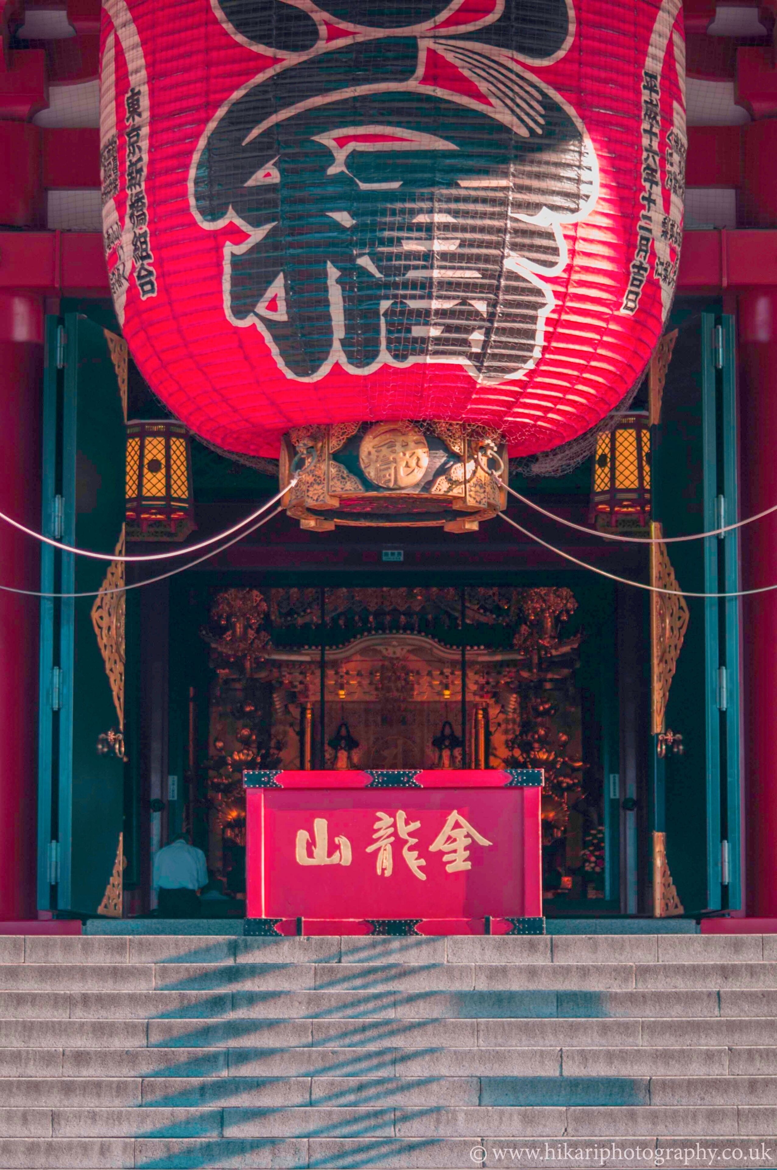 A traditional Japanese building with a red lantern and a sign with Chinese characters.