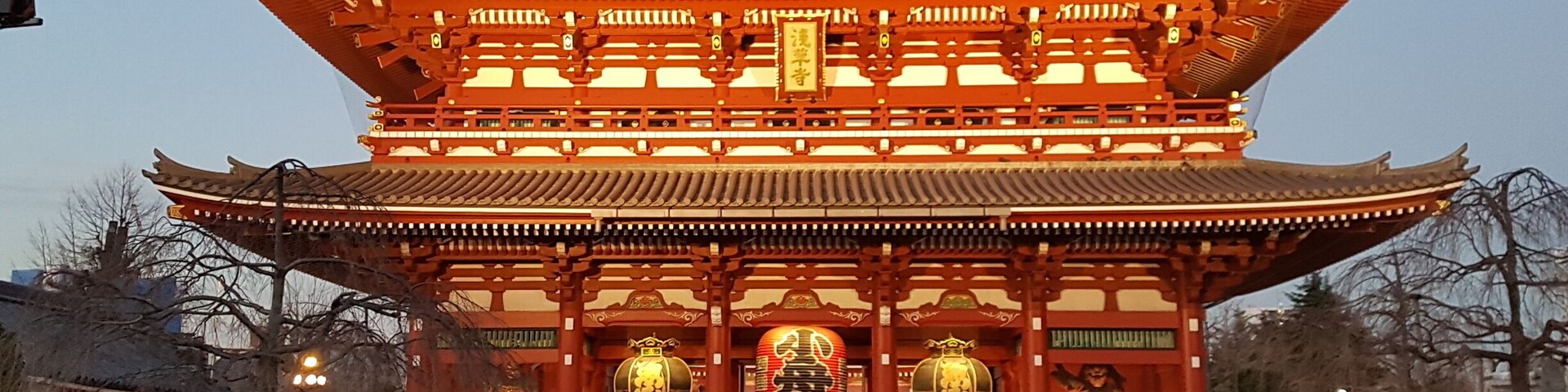 Um templo japonês tradicional com um grande portão ricamente decorado e uma multidão de pessoas na frente.