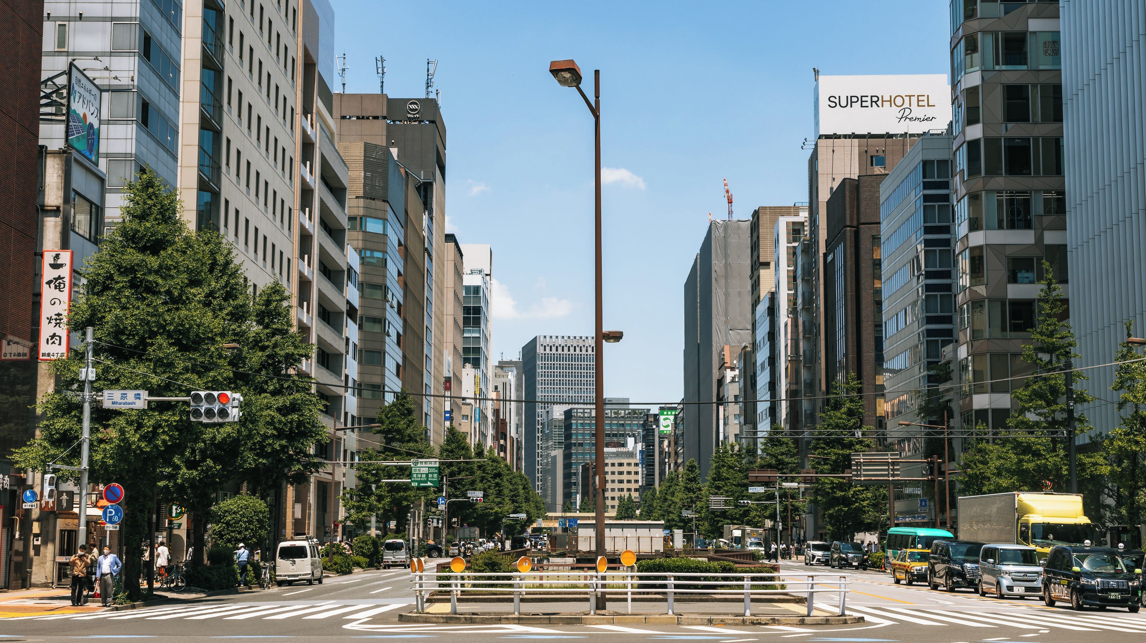 Uma rua urbana movimentada com edifícios modernos, semáforos e uma faixa de pedestres.