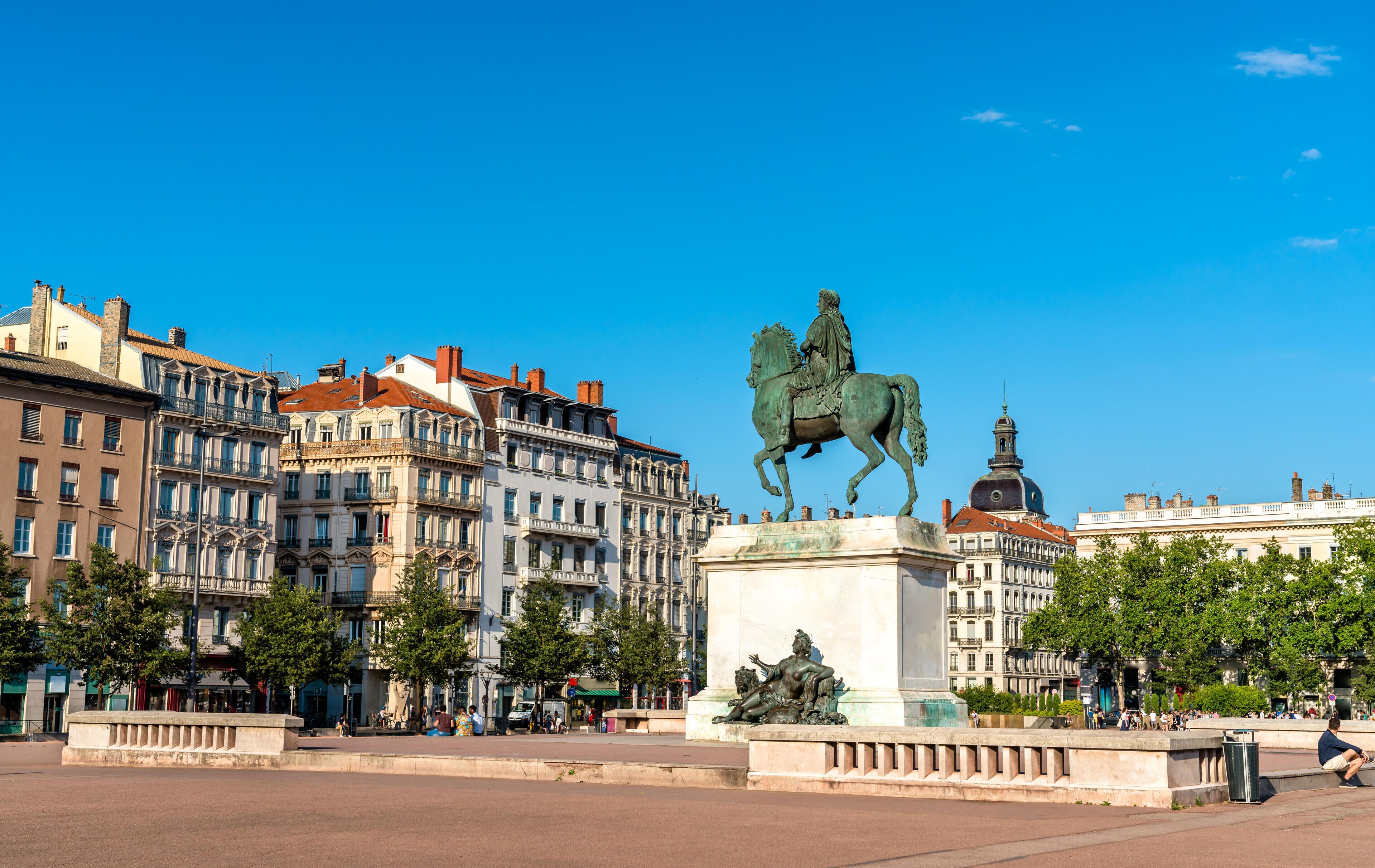 Estátua de um homem a cavalo numa praça, com edifícios históricos ao fundo.