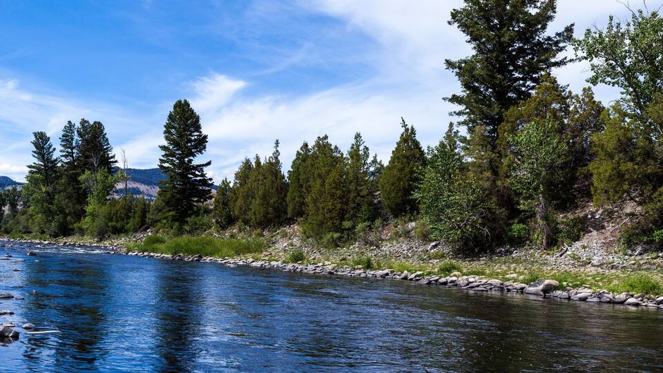 A river with clear blue water, surrounded by trees and rocks.