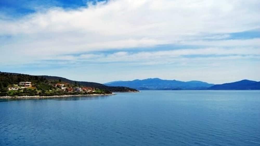 Ein ruhiger See mit einer kleinen Insel und Bergen im Hintergrund.