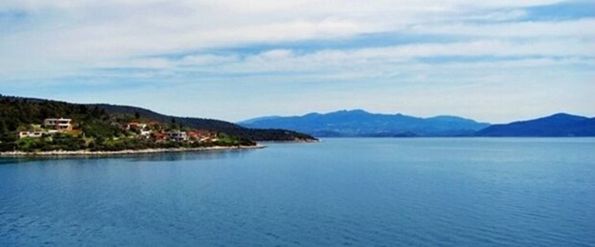 A calm lake with a small island and mountains in the background.
