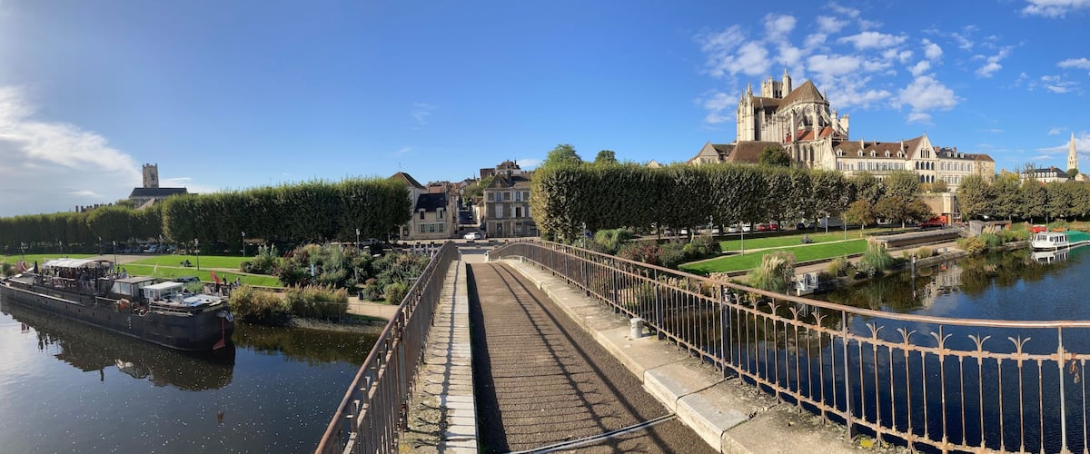 A river with a bridge, a large historic building, and a tower.