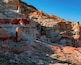 A rugged canyon with layered rock formations and sparse vegetation.