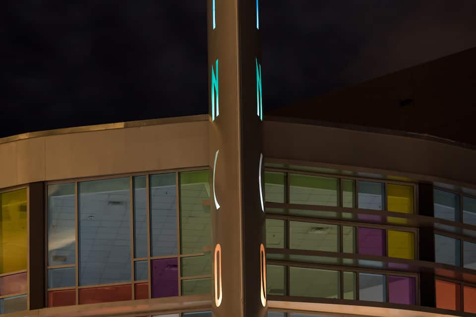 A building with colorful glass windows and a neon sign.