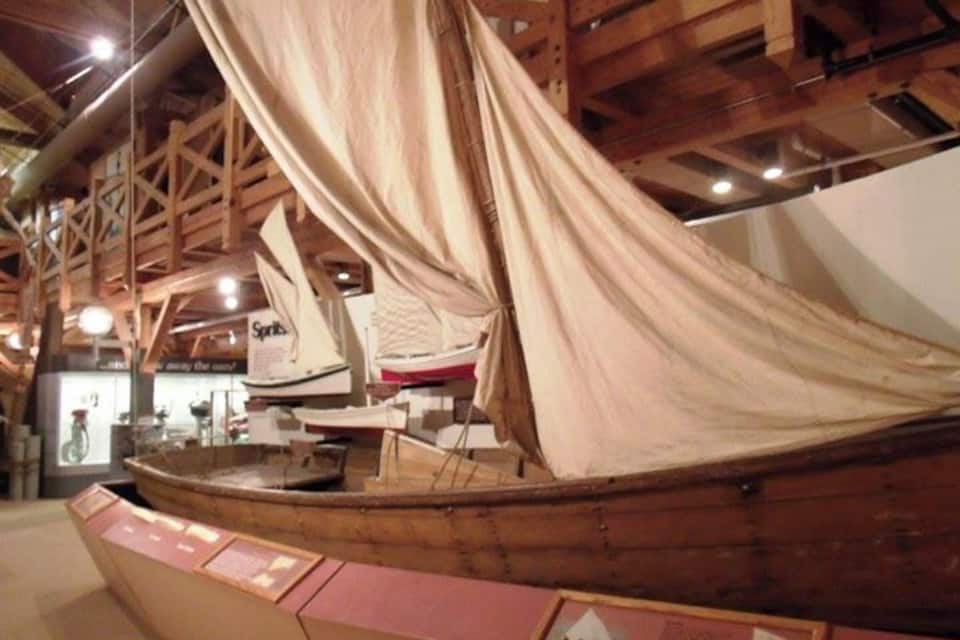Um modelo de navio a vela em exposição sobre construção naval em madeira.