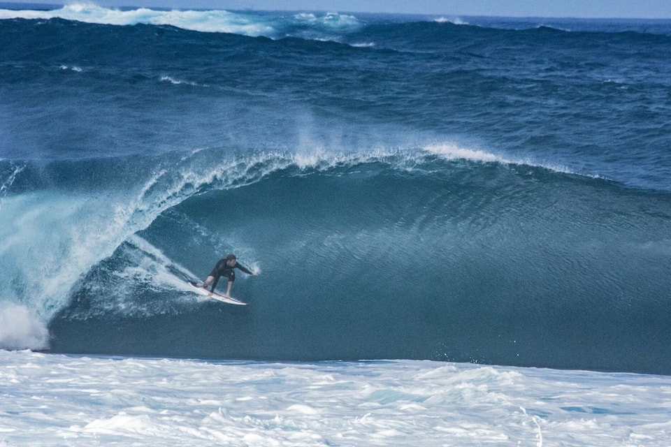 Ein Surfer reitet auf einer hohen Welle im Meer.