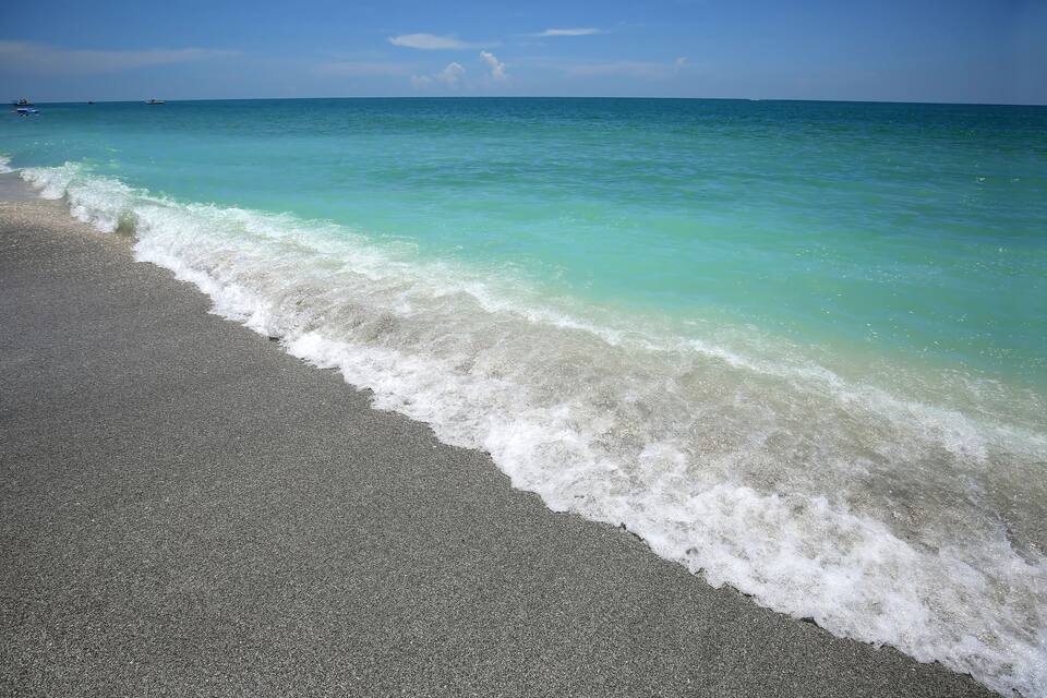 Une plage à l’eau turquoise et limpide, avec de douces vagues.