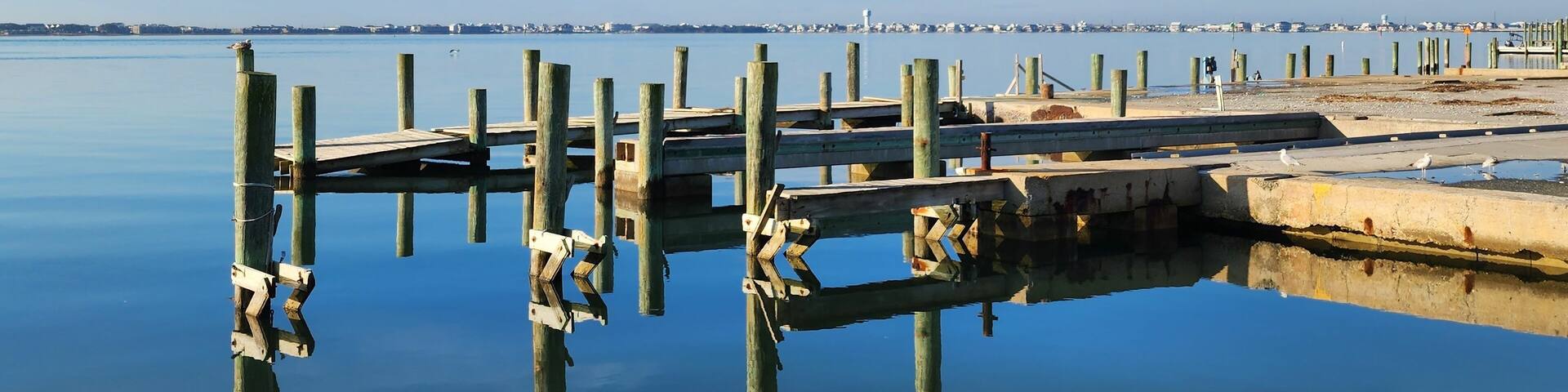 A calm waterfront with wooden piers and a distant city skyline.