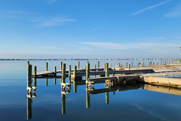 A calm waterfront with wooden piers and a distant city skyline.