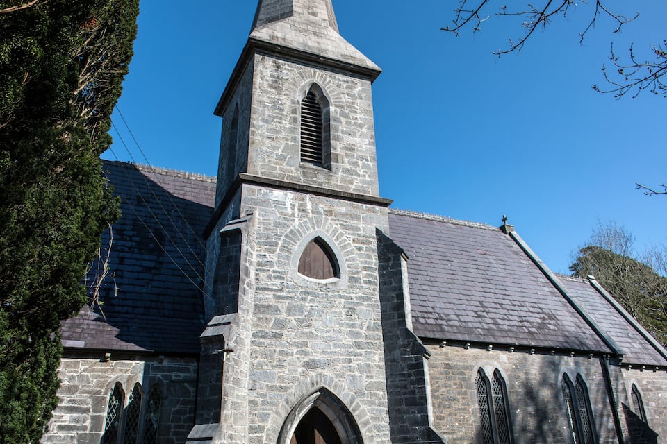 A stone church with a tall steeple and arched windows.