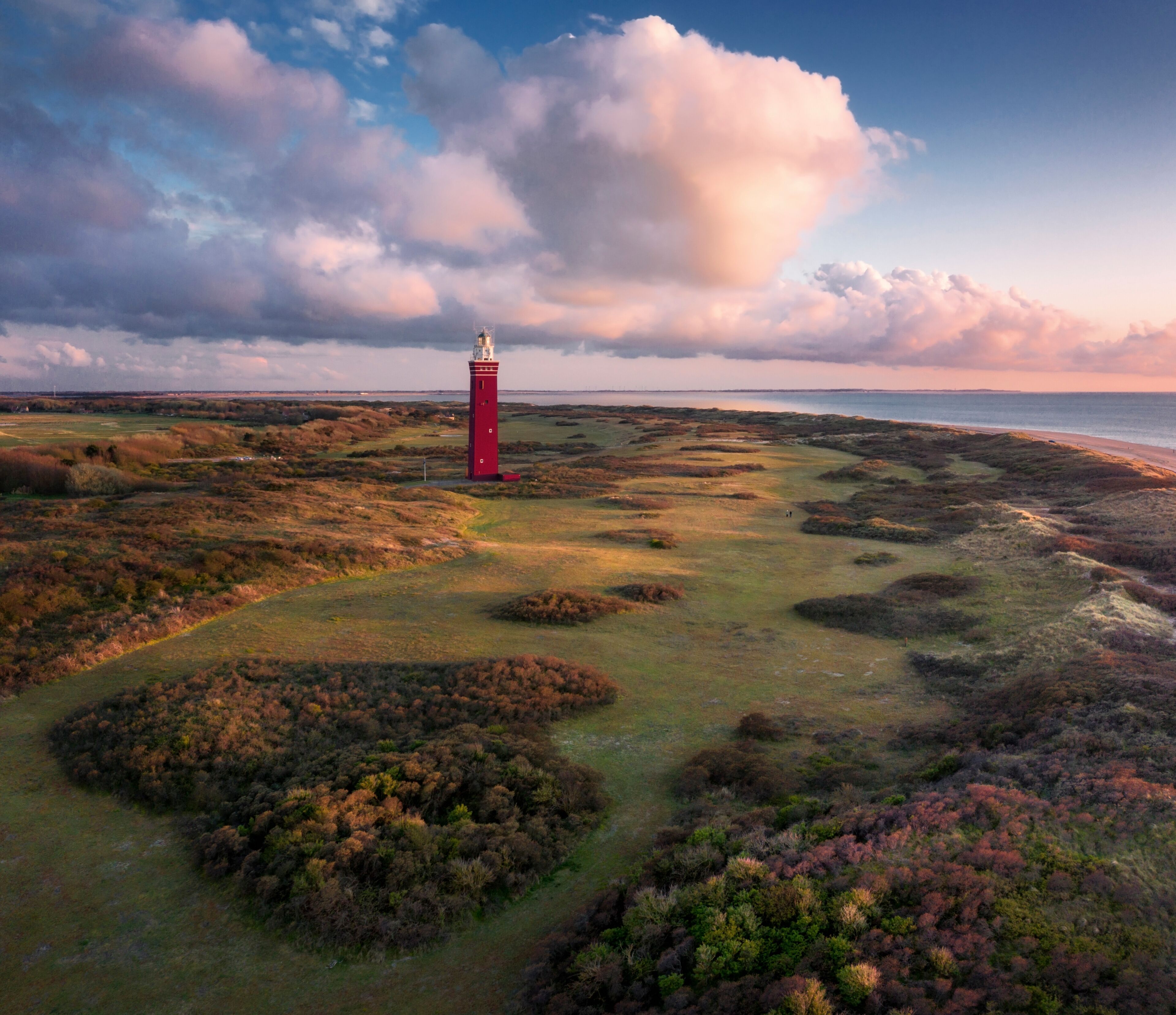Aerial view of Vuurtoren Westhoofd lighthouse along the coast at sunset, Ouddorp, The Netherlands.