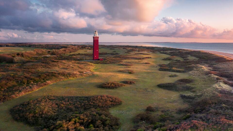 Aerial view of Vuurtoren Westhoofd lighthouse along the coast at sunset, Ouddorp, The Netherlands.