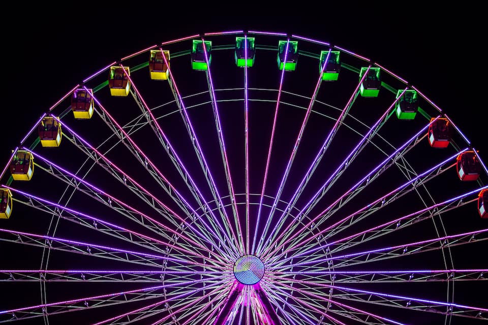 Uma roda gigante bem iluminada com várias cabines à noite.