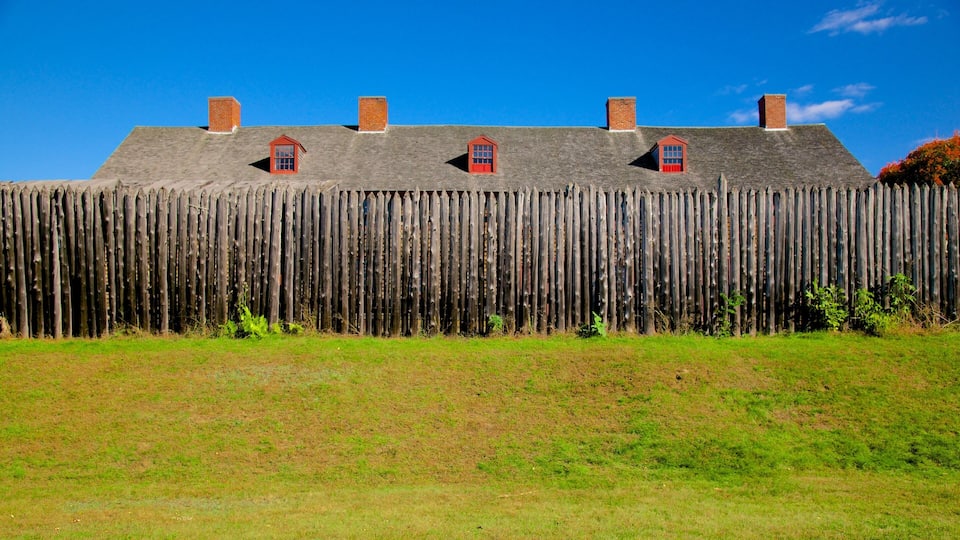 A wooden fence with three small red-roofed buildings on top.