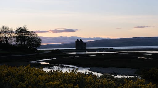 Silhouetted historical Scottish landmark of Lochranza Castle overlooking ocean and loch in rural countryside of Isle of Arran in Inner Hebrides, Scotland UK