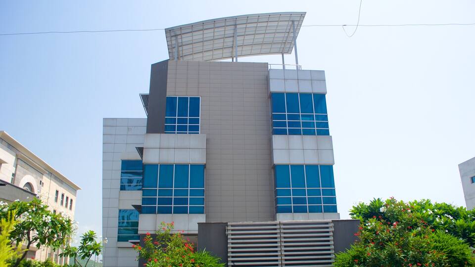 A modern building with a unique rooftop design, large windows, and surrounding greenery.