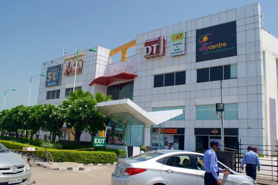 A multi-story commercial building with various storefronts, including a DT cinema and a City Centre DLF Chandigarh.