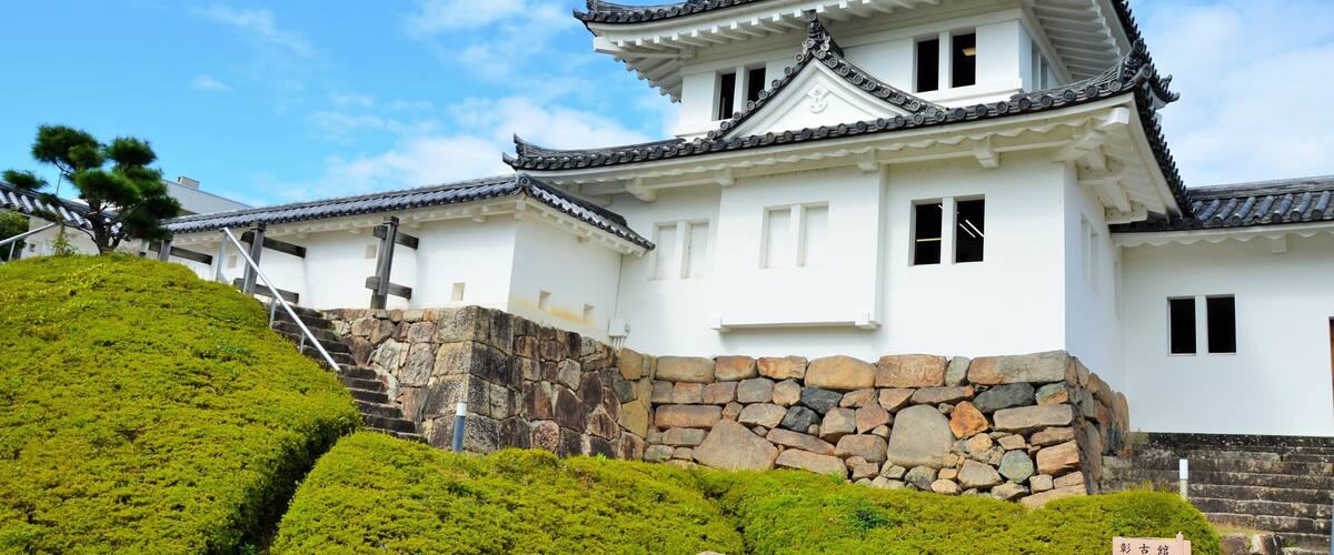 A traditional Japanese castle with white walls, black tiled roofs, and stone walls.