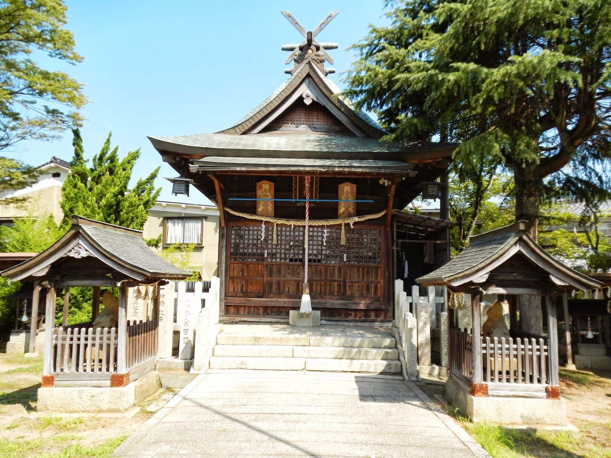 A traditional Japanese gate with a wooden structure, a tiled roof, and a stone pathway leading up to it.