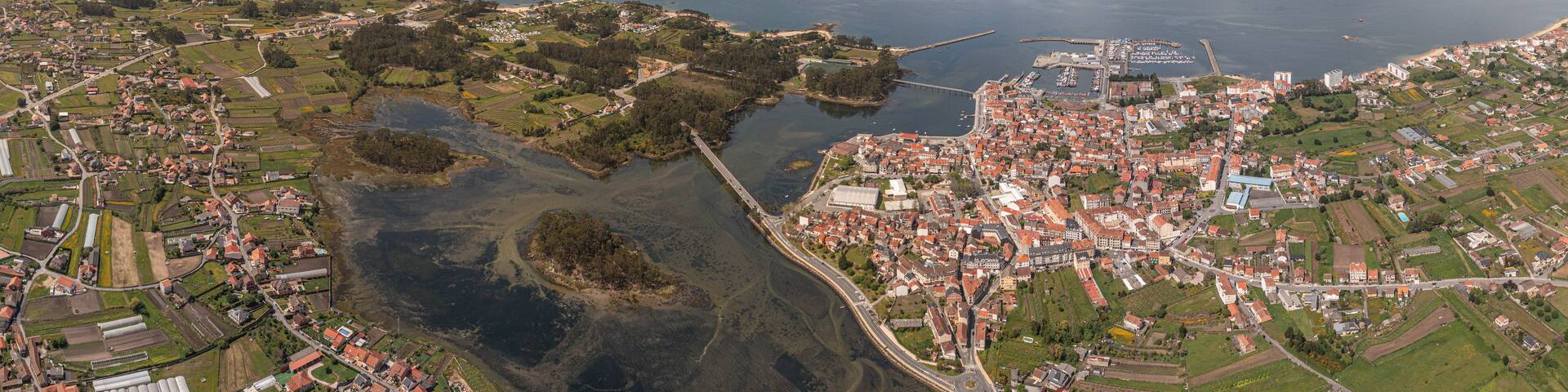 Aerial view of Vilanova de Arousa featuring its coastal town, bridge, and surrounding landscape under a cloudy sky in Vilanova de Arousa, Pontevedra, Spain.