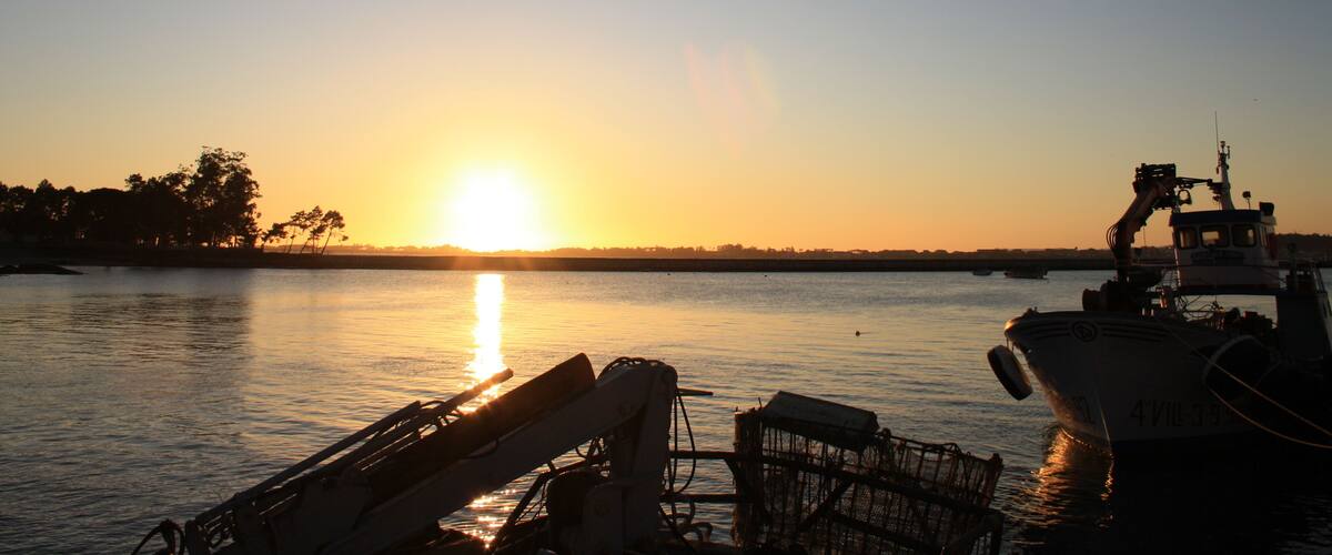 A sunset over a calm body of water with a boat docked on the right.