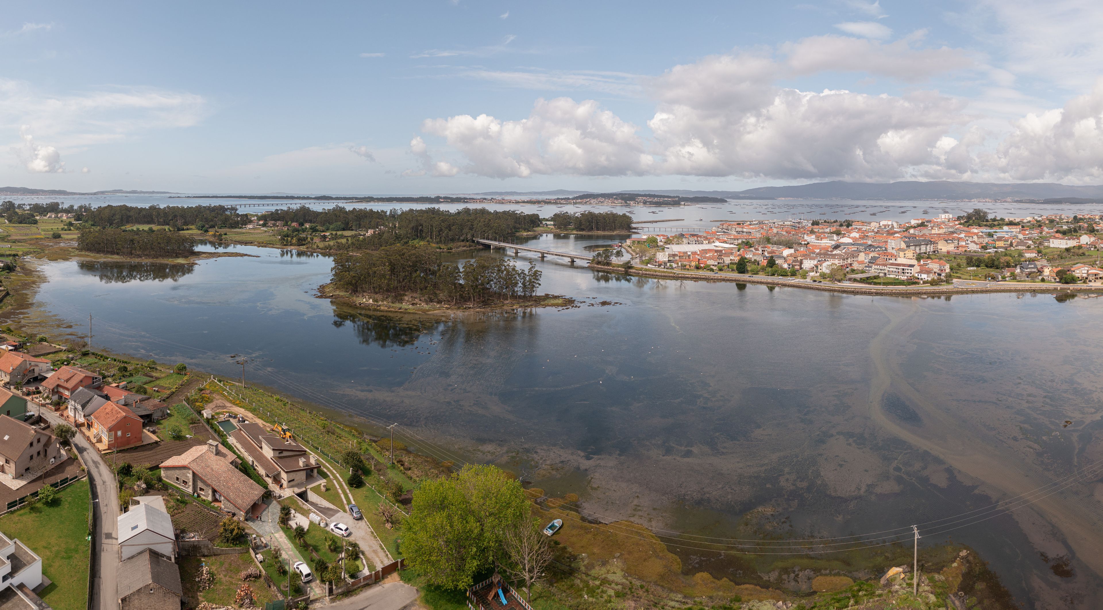 Aerial view of the coastal town of Vilanova de Arousa with its bridge, estuary, and surrounding houses in Vilanova de Arousa, Pontevedra, Spain.