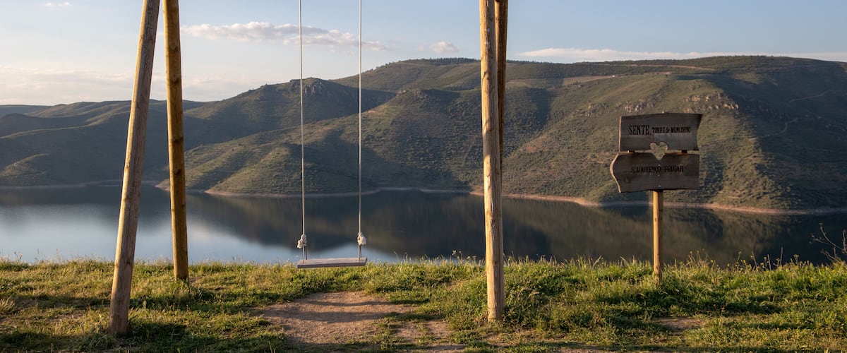 A wooden swing set with a sign indicating 'Sente Torre de Moncorvo' and 'S. Lourenço - Felgar'.