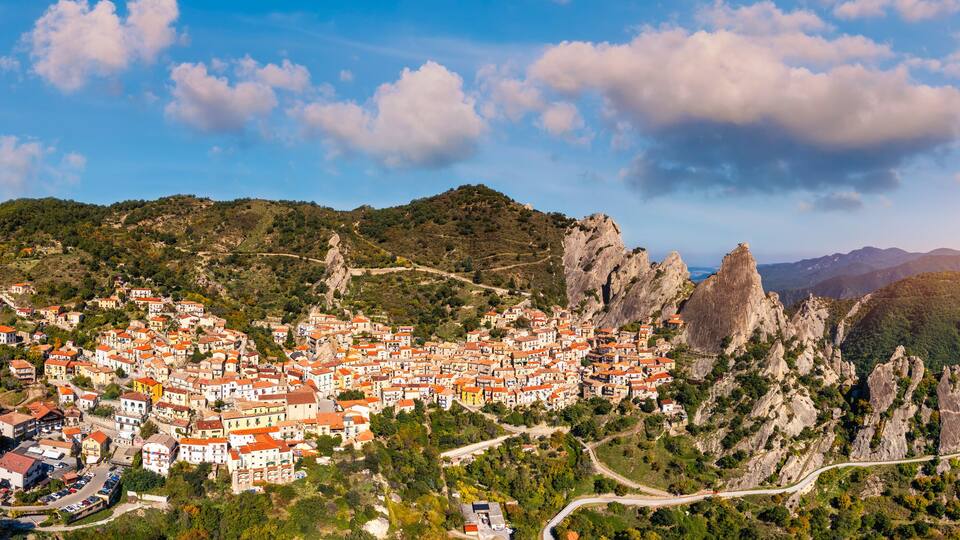 A town nestled in a mountainous area with red-roofed buildings and rocky cliffs.