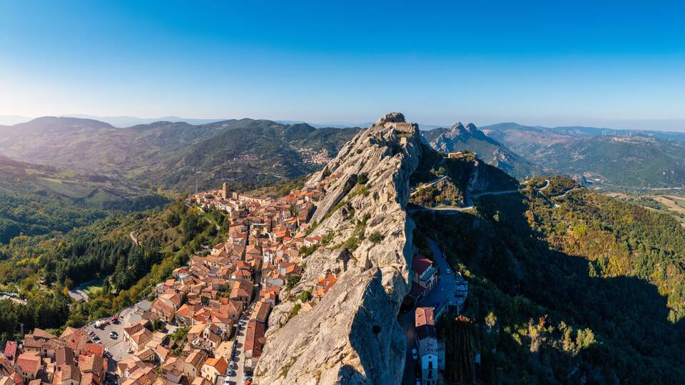 A town perched on a mountain ridge with a historic castle on top.