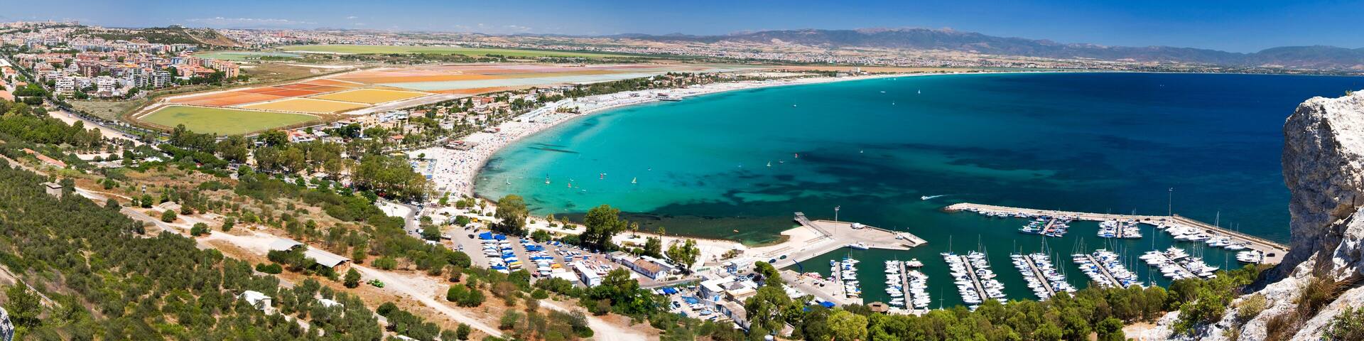 A coastal town with a marina, sandy beaches, and a sports field.