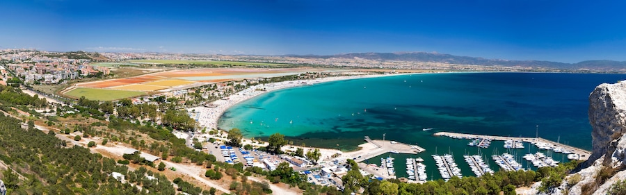 Un pueblo costero con un puerto deportivo, playas de arena y un campo de deportes.