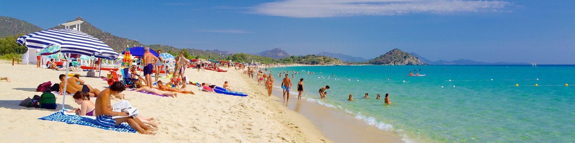 Cala Sinzias featuring a sandy beach as well as a large group of people